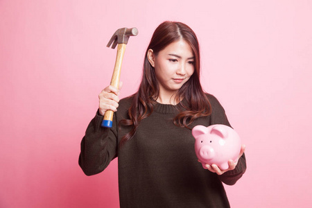 亚洲女人与猪硬币银行和锤子