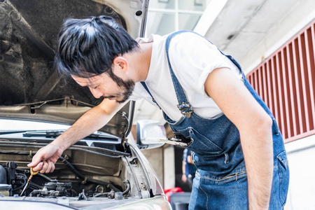 汽车修理车库的汽车发动机修理。英俊的技工