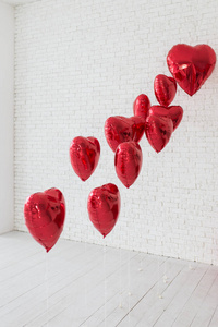 许多红色的气球在心脏的形状。多个红色, 氦填充, 心形气球漂浮在一起的空气与卷曲的丝带