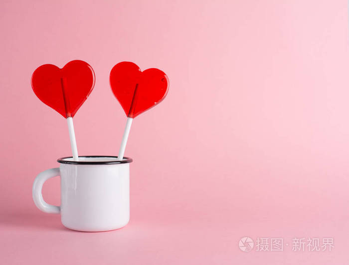 两颗糖果心在杯中的时尚粉红背景最小