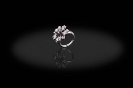白色金宝石戒指女性在形状的花朵与钻石黑色背景。良好的文章或帖子材料