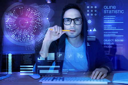 咬铅笔英俊的程序员皱眉和咬铅笔, 而思考照片