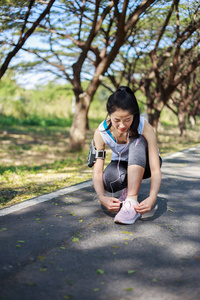 运动妇女在听音乐与 earph 绑鞋带