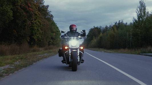 一个人骑摩托车在森林里的道路上