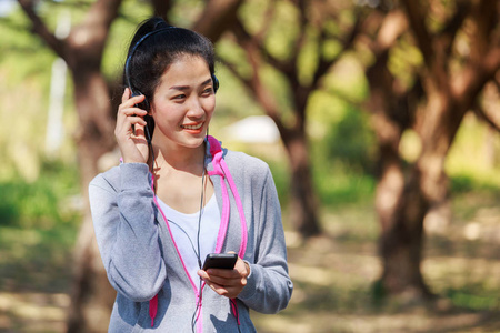 年轻的运动妇女使用智能手机与耳机在公园