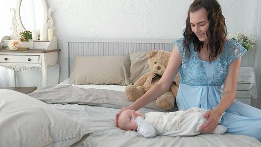 跟踪母亲在走路的时候把婴儿哄入睡。有魅力的女人手牵着婴儿, 穿过起居室, 背景是明亮的窗帘