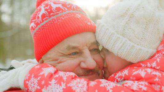 小男孩在冬天公园亲吻他的祖父面颊