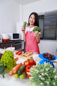 厨房里拿着花椰菜和黄瓜的女人