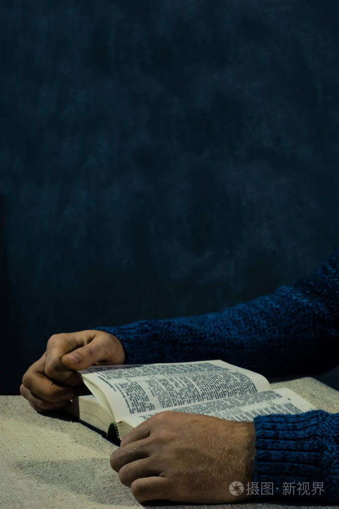 坐在桌子上读圣经的年轻人