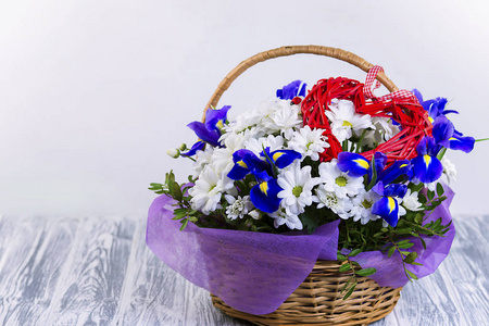 白色雏菊和蓝色公鸡的美丽的花束在木篮子里