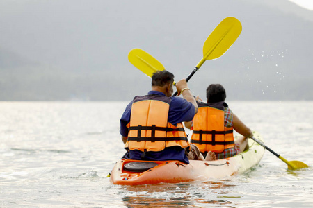 海岛的背景下, 男人和女人在海里的独木舟上游泳。