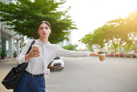 漂亮的商务女士与咖啡杯在她的手赶上出租车