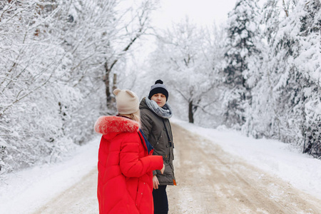一对美丽的家庭情侣走在雪地上的道路在树林里