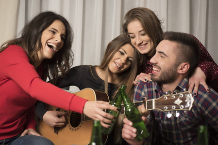 在家玩吉他喝啤酒和唱歌的朋友图片