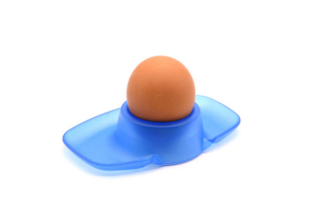 米色天然蛋在蓝色塑料蛋杯子在白色被隔绝的 ba