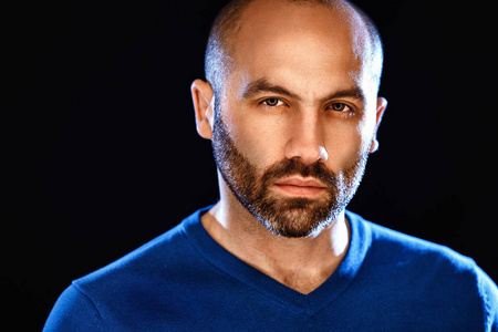 帅留胡子的年轻人看着相机站在灰色背景下的肖像照片