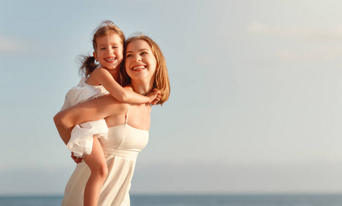 海滩快乐的家庭。母亲拥抱孩子的女儿