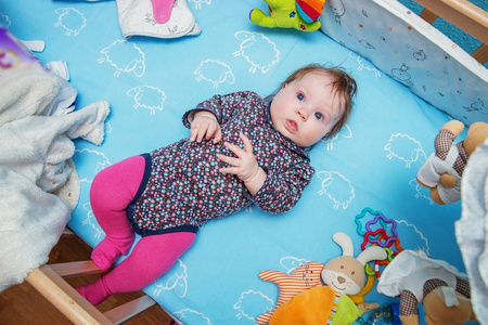 一个可爱的婴儿躺在她的婴儿床上的玩具