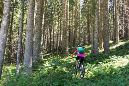 活跃运动的妇女骑山地自行车在森林足迹
