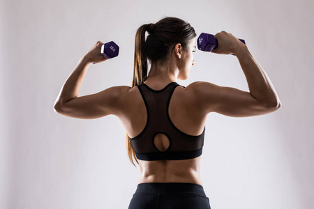 相片拜访年轻女子健美运动员用哑铃做运动.