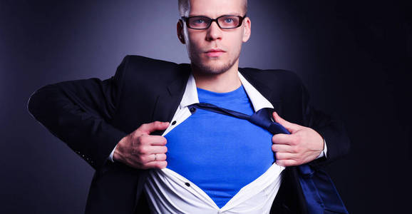 年轻商人喜欢的超级英雄和撕裂他的衬衫，灰色的背景上孤立