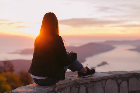妇女坐在山上看日落