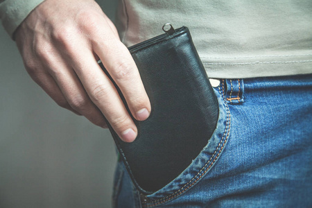黑色的牛仔裤的口袋里男人从牛仔裤口袋里掏出黑色钱包.照片