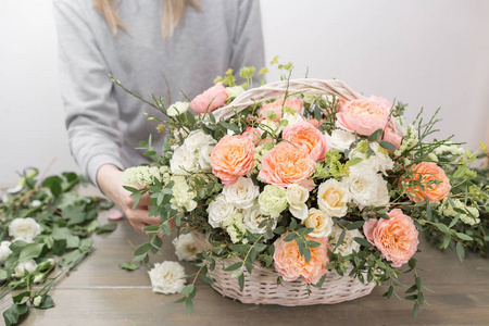 特写手女花店。花卉车间妇女制作一个美丽的花朵组合在一个柳条篮子花束。植物理念