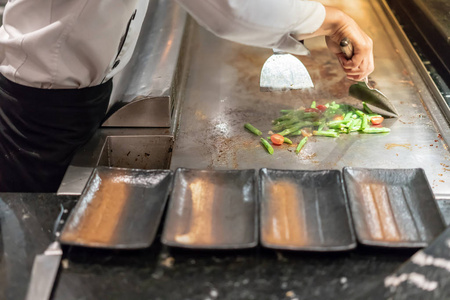 厨师烹饪沙拉上热的平底锅，在客户面前的手