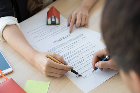 房地产中介代理形象协助客户用房屋模型在办公桌上签合同文件照片