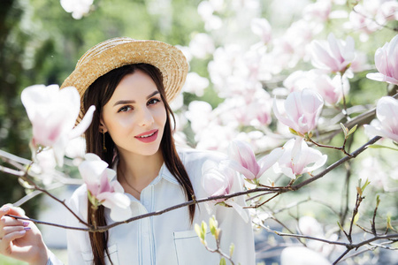 春天花园里木兰粉红色花树的年轻美女