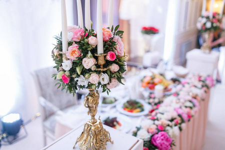 在餐厅的豪华婚宴上, 金属金色吊灯上的白色蜡烛站在桌上。时尚的装饰和装饰