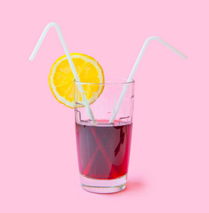新鲜果汁玻璃与稻草片黄色柠檬在粉红色的背景。时尚柔和的夏日设计风格理念