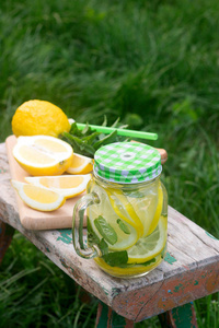 自制柠檬水与薄荷和冰在一个木凳在花园里。乡村风格