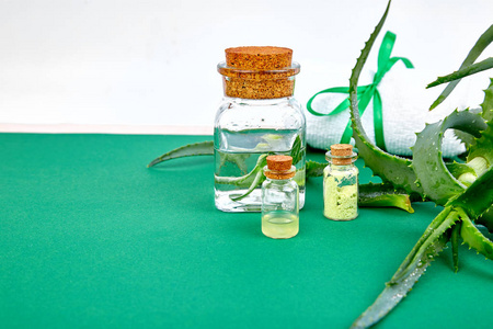 芦荟油在玻璃瓶和毛巾的温泉在绿色的背景。星仙人掌, 芦荟, Jafferabad, 芦荟芦荟, 巴巴多斯草药为皮肤治疗和护理。复