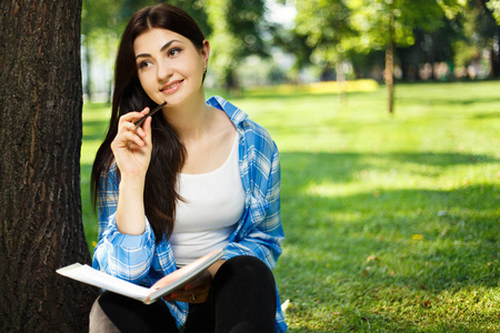 女学生在笔记本上做笔记。年轻妇女坐