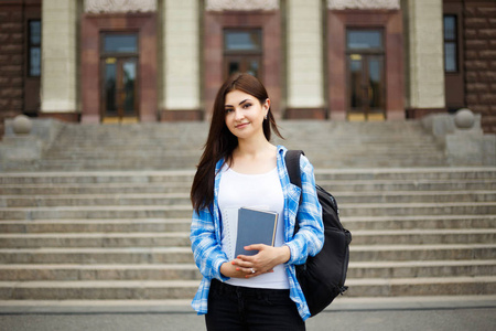 学生女孩与书和背包站立在大学附近