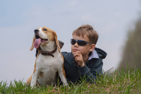 欧洲男孩与猎犬狗躺在草地上