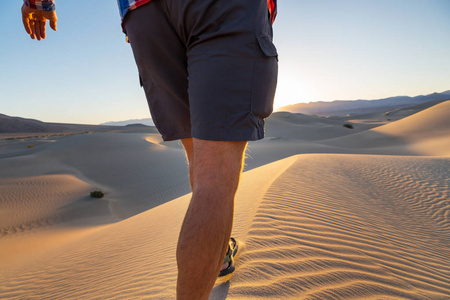 徒步旅行者在沙子沙漠接近的腿