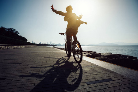 骑自行车的剪影在日出海岸路