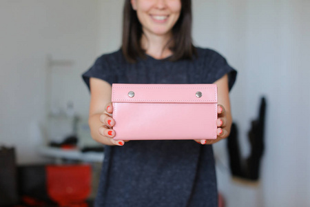 女性微笑的人站在粉红色皮革手工钱包在家里的画室里