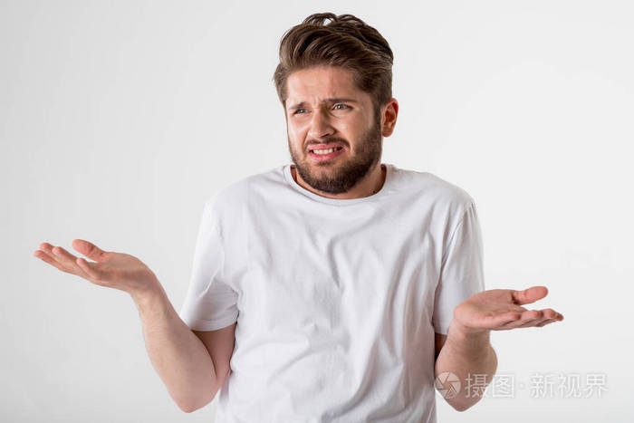 灰色背景下的白色衬衫上的年轻反感胡子男子肖像