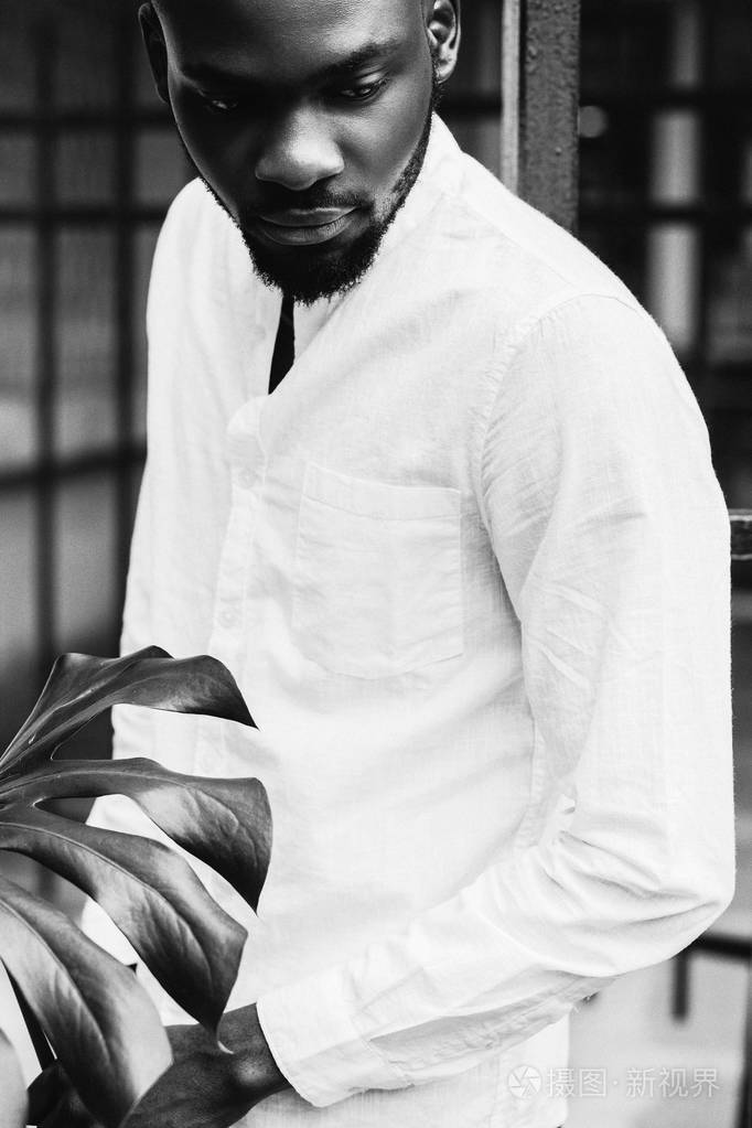 手持棕榈叶的美国休闲黑人男子黑白肖像