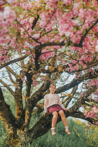盛开的樱花的春天的形象。小女孩玩装饰樱桃树, 快乐童年在农村