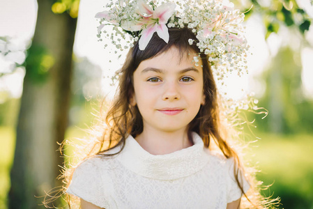 一个年轻的女孩的肖像在她的头上草地上的花朵花圈