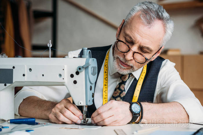 专注的成熟裁缝工作与缝纫机在车间