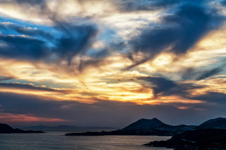 壮观的日落或日出与饱和的天空和云彩。风景秀丽日落在海和岩石之上。自然背景