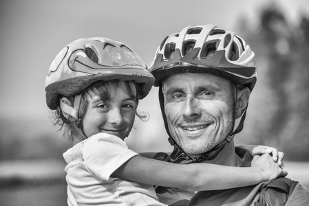 父亲和女儿与自行车头盔快乐享受 ciy 公园