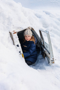可爱的小女孩户外在美丽的冬天在一个汽车覆盖雪后大雪