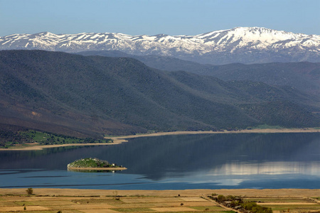 在春天的山丘和积雪覆盖的山峰之间的湖泊景观。迪沃的自治市, 在西部马其顿地区, 希腊